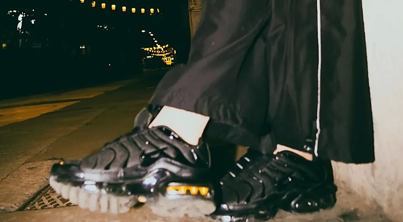 Nike Air Max Plus negras de charol en una calle de noche